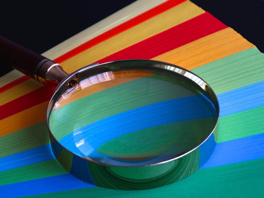 magnifying glass on multicolored strips of paper