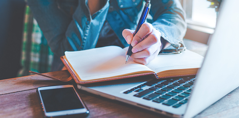 Person working at computer and writing in notebook about content marketing